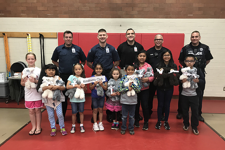 Students in the Ogden Kindness Club present teddy bears they made to police officers