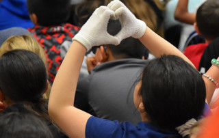 Student makes the heart symbol with their hands