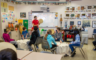 Teacher leads class in drumming exercise