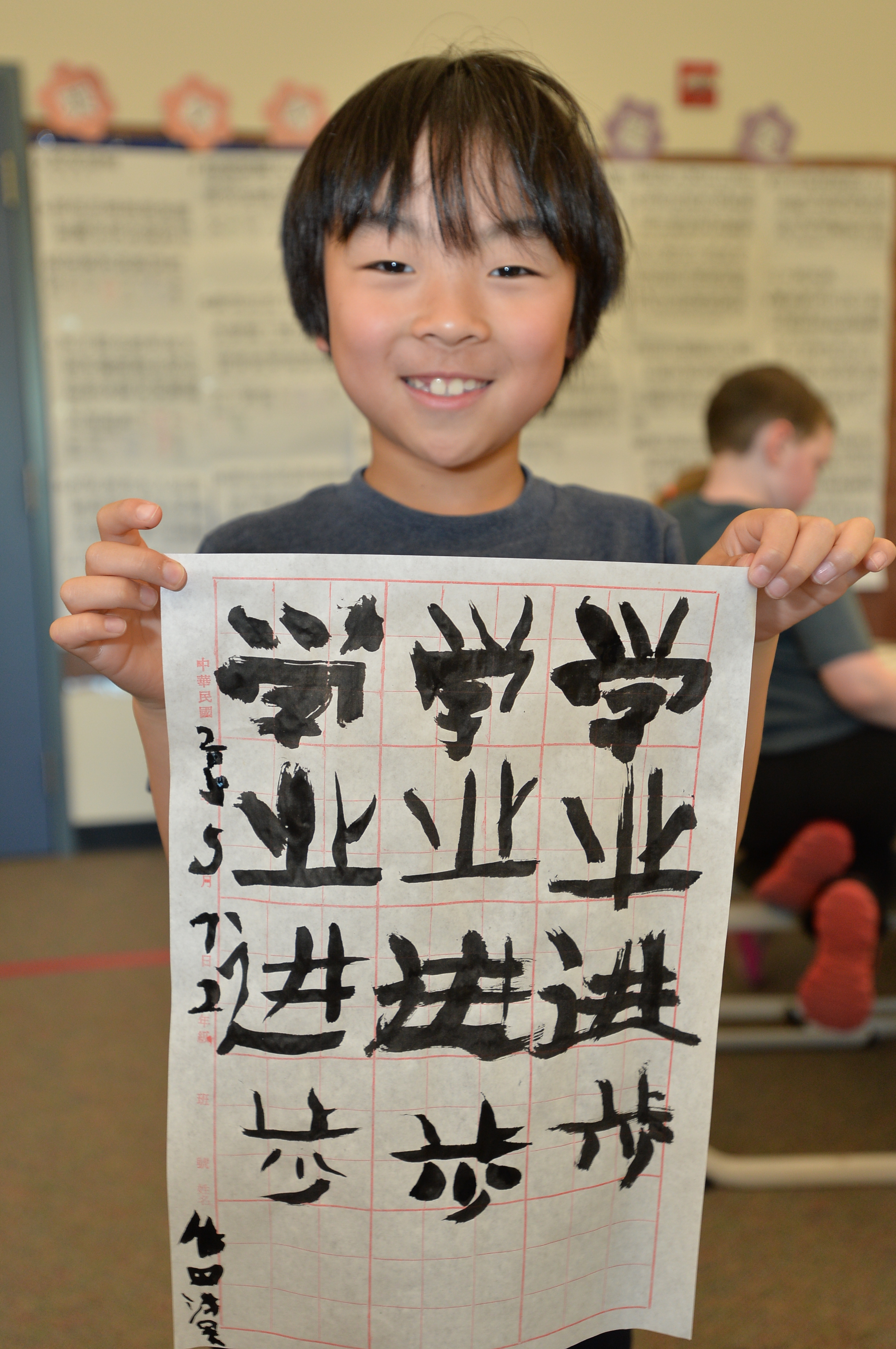 Student in classroom holding up chinese lettering