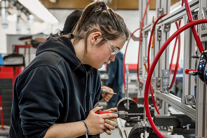 Advanced Manufacturing student drilling metal.